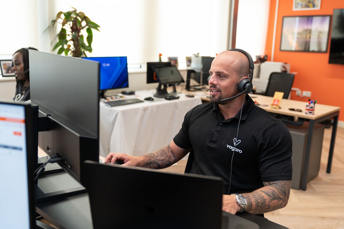A customer support specialist wearing a headset at a computer.